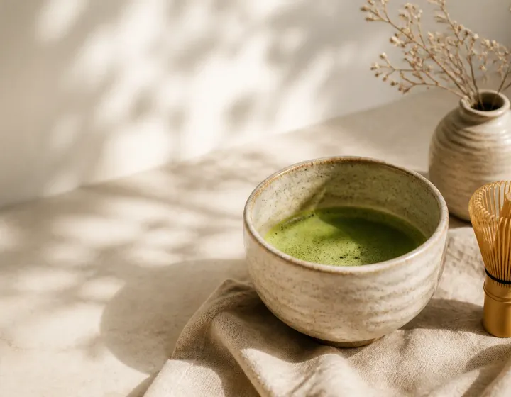 En kop nypisket matcha ved siden af en bambusvisp